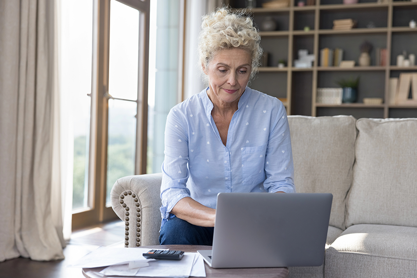 Serious senior woman sit at table in living room