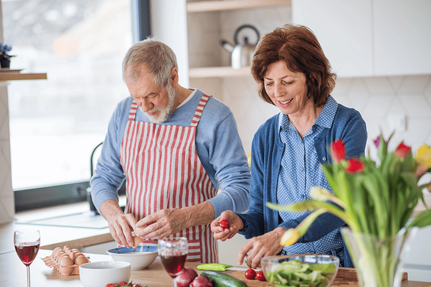 a portrait of senior couple in love cooking together