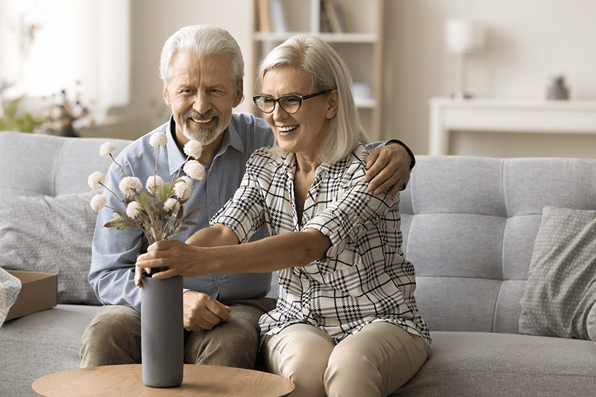 happy senior wife arranging bunch of flowers given by her husband 