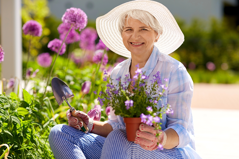 Senior woman planting flowers at summer garden